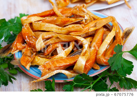 Smoked salmon belly strips on plate on wooden table Smoked salmon belly strips on plate on wooden table 67075776