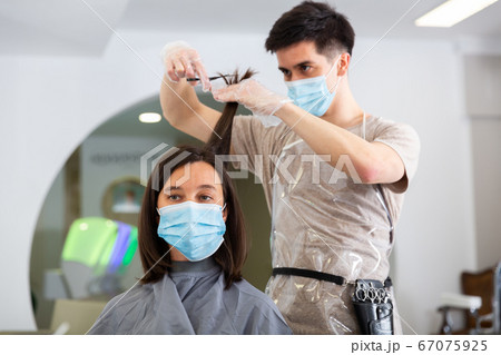 Woman client in mask during cuts hair at beauty salon Woman client in mask during cuts hair at beauty salon 67075925
