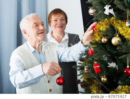 Aged couple decorating Christmas tree Aged couple decorating Christmas tree 67075927