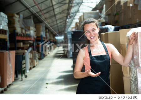 Portrait of female worker in apron with arms crossed standing in warehouse 67076380