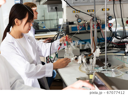 Chinese girl working with reagents in test tubes during chemical experiment Chinese girl working with reagents in test tubes during chemical experiment 67077412