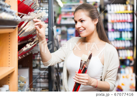 Merry woman shopping various paintbrushes 67077416