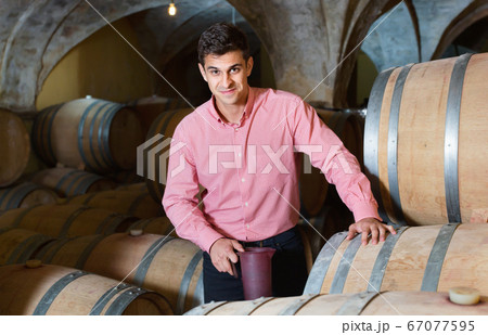 Male customer tasting red wine from wooden barrels 67077595