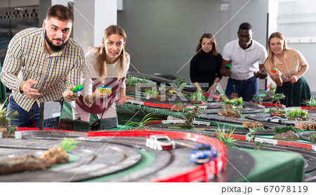 Young couples play a game slot car racing track Young couples play a game slot car racing track 67078119