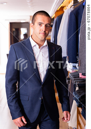 Portrait of male client choosing classic jacket in the mall Portrait of male client choosing classic jacket in the mall 67078864