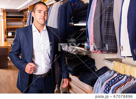 Portrait of male client choosing classic jacket in the mall Portrait of male client choosing classic jacket in the mall 67078896