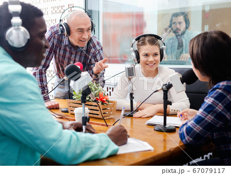 Multinational group of cheerful young adults emotionally discussing in radio studio 67079117