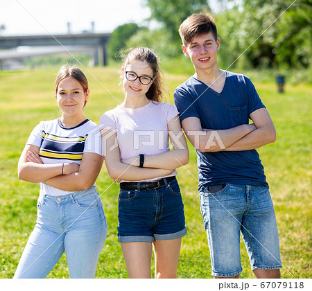 Positive teenagers posing on the spring park lawn 67079118