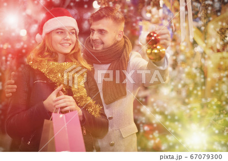 Joyful couple in Christmas hat with Christmas toys at fair 67079300