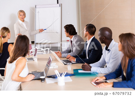 Woman reading out report to colleagues 67079732