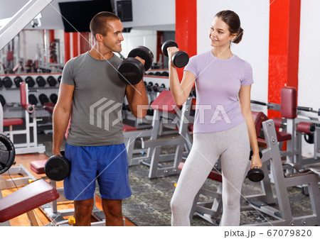 Man and woman posing with dumbbells Man and woman posing with dumbbells 67079820
