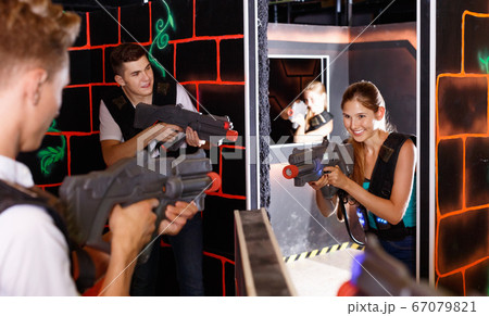 Two laser tag teams playing enthusiastically and aiming at each other in dark room 67079821