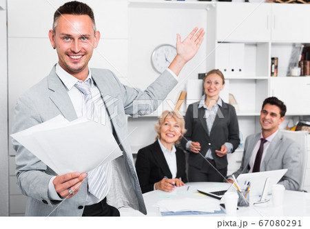 Happy entrepreneur with papers standing in office 67080291