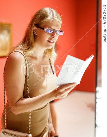 Woman with booklet looking at exhibits Woman with booklet looking at exhibits 67080751