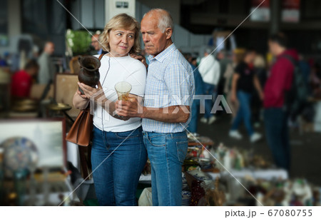 Smiling mature spouses buying retro handicrafts on flea market 67080755