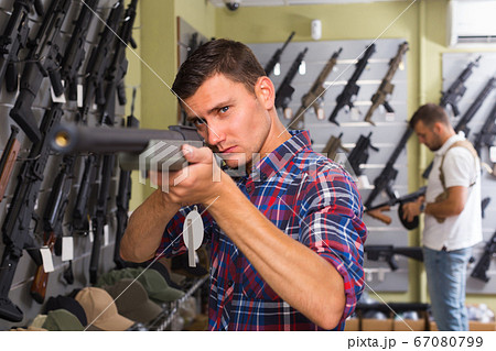 Portrait of adult male which is choosing air-powered gun Portrait of adult male which is choosing air-powered gun 67080799