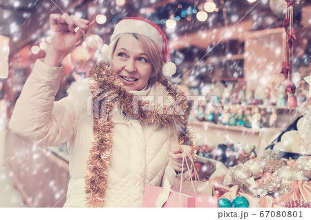 Woman is preparing for Christmas and choosing balls on the tree Woman is preparing for Christmas and choosing balls on the tree 67080801
