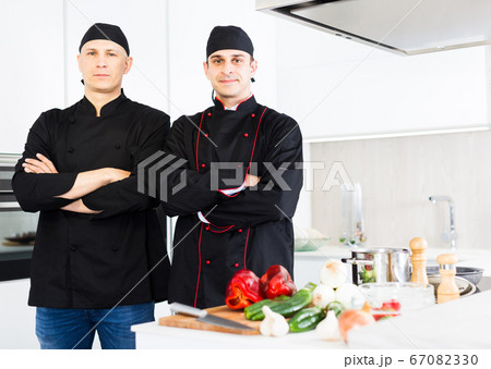 Young male chefs in black uniform standing near workplace 67082330