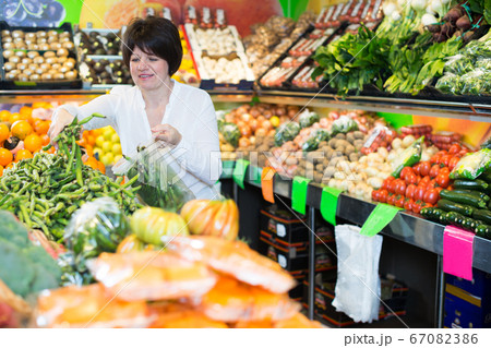 Mature woman buying fresh vegetables Mature woman buying fresh vegetables 67082386