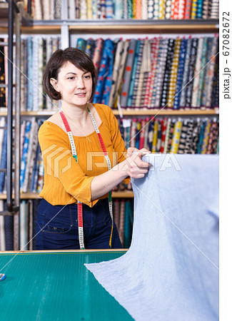 Saleswoman measuring cloth for cutting 67082672