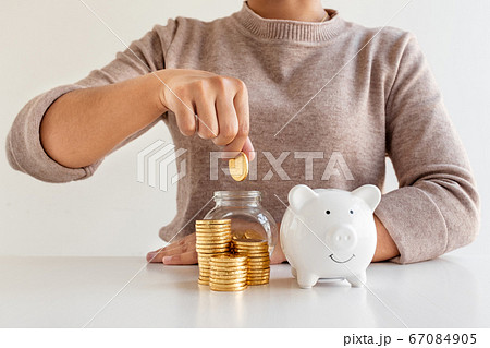 Women are putting coins in a piggy bank, glass bottle, saving money with coins, stepping into a growing business to succeed, and save for retirement Women are putting coins in a piggy bank, glass bottle, saving money with coins, stepping into a growing business to succeed, and save for retirement 67084905