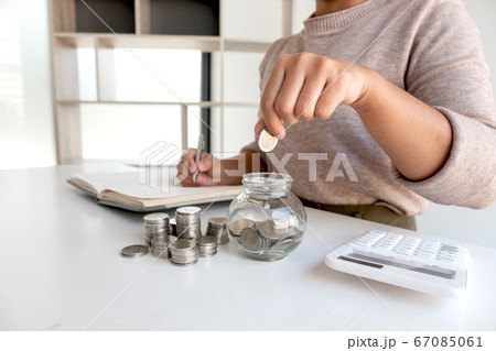 Women are putting coins in a piggy bank, glass bottle, saving money with coins, stepping into a growing business to succeed, and save for retirement Women are putting coins in a piggy bank, glass bottle, saving money with coins, stepping into a growing business to succeed, and save for retirement 67085061