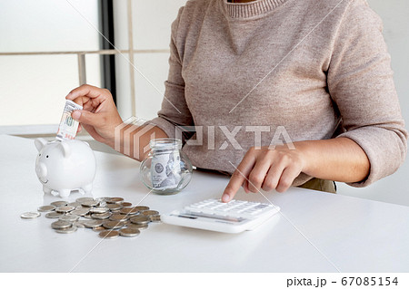 Women are putting dollar notes in a piggy bank with money-saving coins. Step into a growing business for success and save for retirement Women are putting dollar notes in a piggy bank with money-saving coins. Step into a growing business for success and save for retirement 67085154