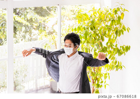 マスクをつけた若い男性(上着を着る・脱ぐ) マスクをつけた若い男性(上着を着る・脱ぐ) 67086618