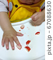 小さくカットしたイチゴをつまもうとする赤ちゃん 67088630
