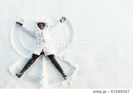 black girl lies on white forest glade and makes snow angles black girl lies on white forest glade and makes snow angles 67089567