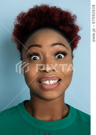 African-american beautiful young woman's close up portrait on blue studio background, emotional and expressive. Copyspace for ad. African-american beautiful young woman's close up portrait on blue studio background, emotional and expressive. Copyspace for ad. 67092638