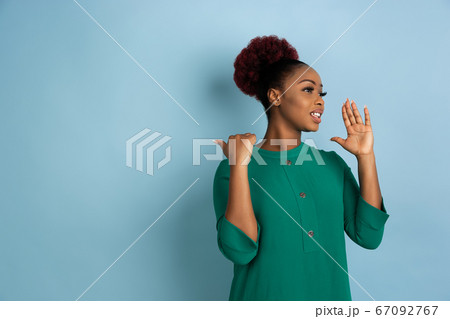 African-american beautiful young woman's portrait on blue studio background, emotional and expressive. Copyspace for ad. African-american beautiful young woman's portrait on blue studio background, emotional and expressive. Copyspace for ad. 67092767