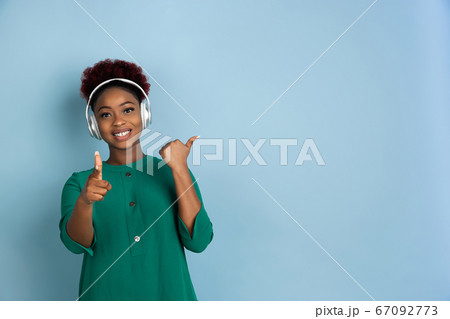 African-american beautiful young woman's portrait on blue studio background, emotional and expressive. Copyspace for ad. African-american beautiful young woman's portrait on blue studio background, emotional and expressive. Copyspace for ad. 67092773
