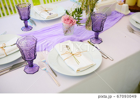 Elegant table setting for wedding engagement Easter dinner with white ceramic plates cotton napkin tied with twine lavender flowers candles. Provence style Elegant table setting for wedding engagement Easter dinner with white ceramic plates cotton napkin tied with twine lavender flowers candles. Provence style 67093049