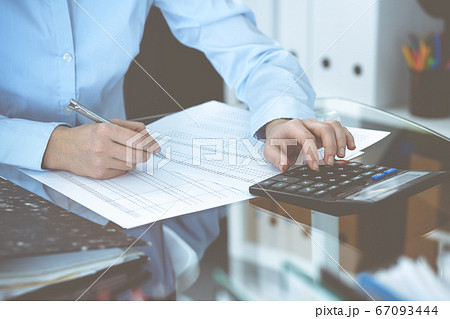 Bookkeeper woman or financial inspector making report, calculating or checking balance, close-up. Business, audit or tax concepts Bookkeeper woman or financial inspector making report, calculating or checking balance, close-up. Business, audit or tax concepts 67093444