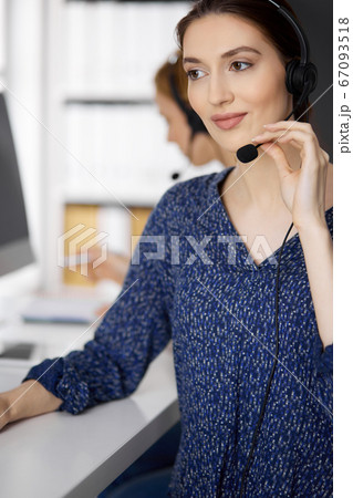 Latin american businesswoman talking by headset while sitting in office. Call center and diverse people group in business Latin american businesswoman talking by headset while sitting in office. Call center and diverse people group in business 67093518