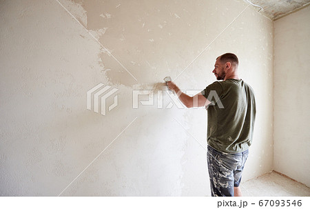 Guy is making repairing in apartment by putting putty on the walls. Guy is making repairing in apartment by putting putty on the walls. 67093546
