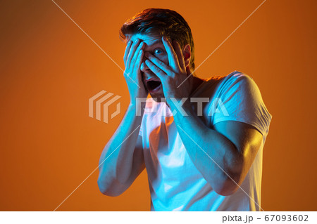 Caucasian beautiful young man's portrait on gradient orange studio background, emotional and expressive. Copyspace for ad. Caucasian beautiful young man's portrait on gradient orange studio background, emotional and expressive. Copyspace for ad. 67093602