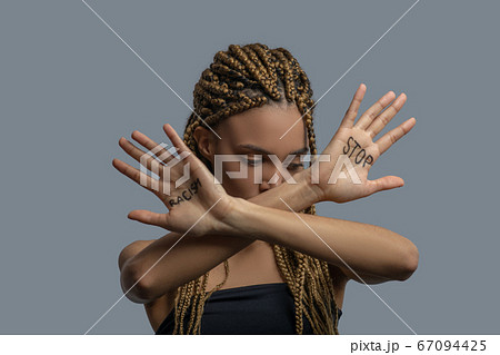 Young African American woman looking down, making cross with arms, showing palm with stop racism lettering Young African American woman looking down, making cross with arms, showing palm with stop racism lettering 67094425