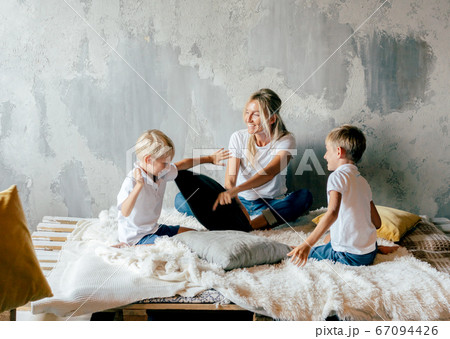 Family plays on the bed with pillows. Battle between mom and sons. Family plays on the bed with pillows. Battle between mom and sons. 67094426