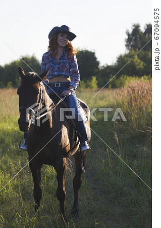 Portrait of a young woman and horse in the meadow at summer evening 67094675
