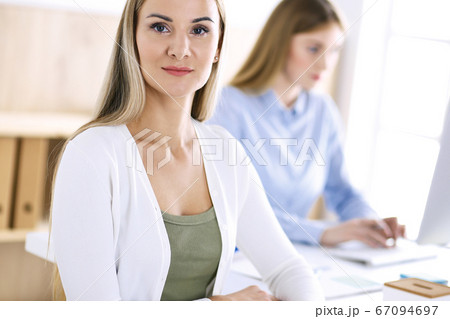 Business woman headshot. Businesspeople or colleagues discussing something at meeting while sitting at the desk in office. Casual clothes style. Audit, tax or lawyer concept Business woman headshot. Businesspeople or colleagues discussing something at meeting while sitting at the desk in office. Casual clothes style. Audit, tax or lawyer concept 67094697