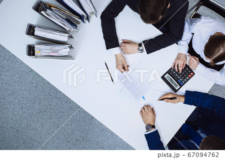 Business people at meeting, view from above. Bookkeeper or financial inspector making report, calculating or checking balance Business people at meeting, view from above. Bookkeeper or financial inspector making report, calculating or checking balance 67094762