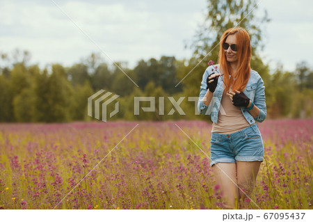 Attractive sexy red-haired model in a summer field with flowers 67095437