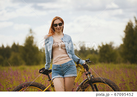 Attractive young woman in sportswear in a flower field with bike 67095452