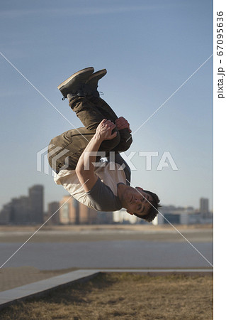 Young man parkour sportsman performs tricks in front of skyline 67095636