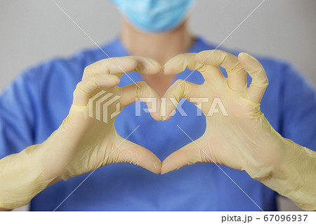 Hands in rubber gloves making the heart symbol in front of a healthcare professional in uniform. Hands in rubber gloves making the heart symbol in front of a healthcare professional in uniform. 67096937