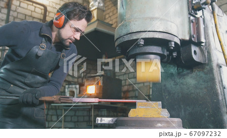 Molten metal is processed under pressure in the hands of a blacksmith 67097232
