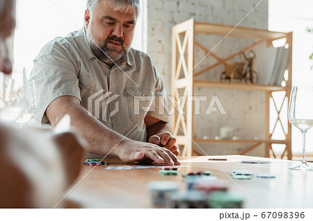 Two happy mature friends playing cards and drinking wine 67098396