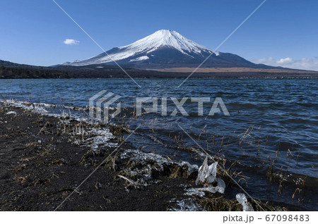 湖畔を打つ波が凍る厳冬期の山中湖と雪を頂く富士山の写真素材